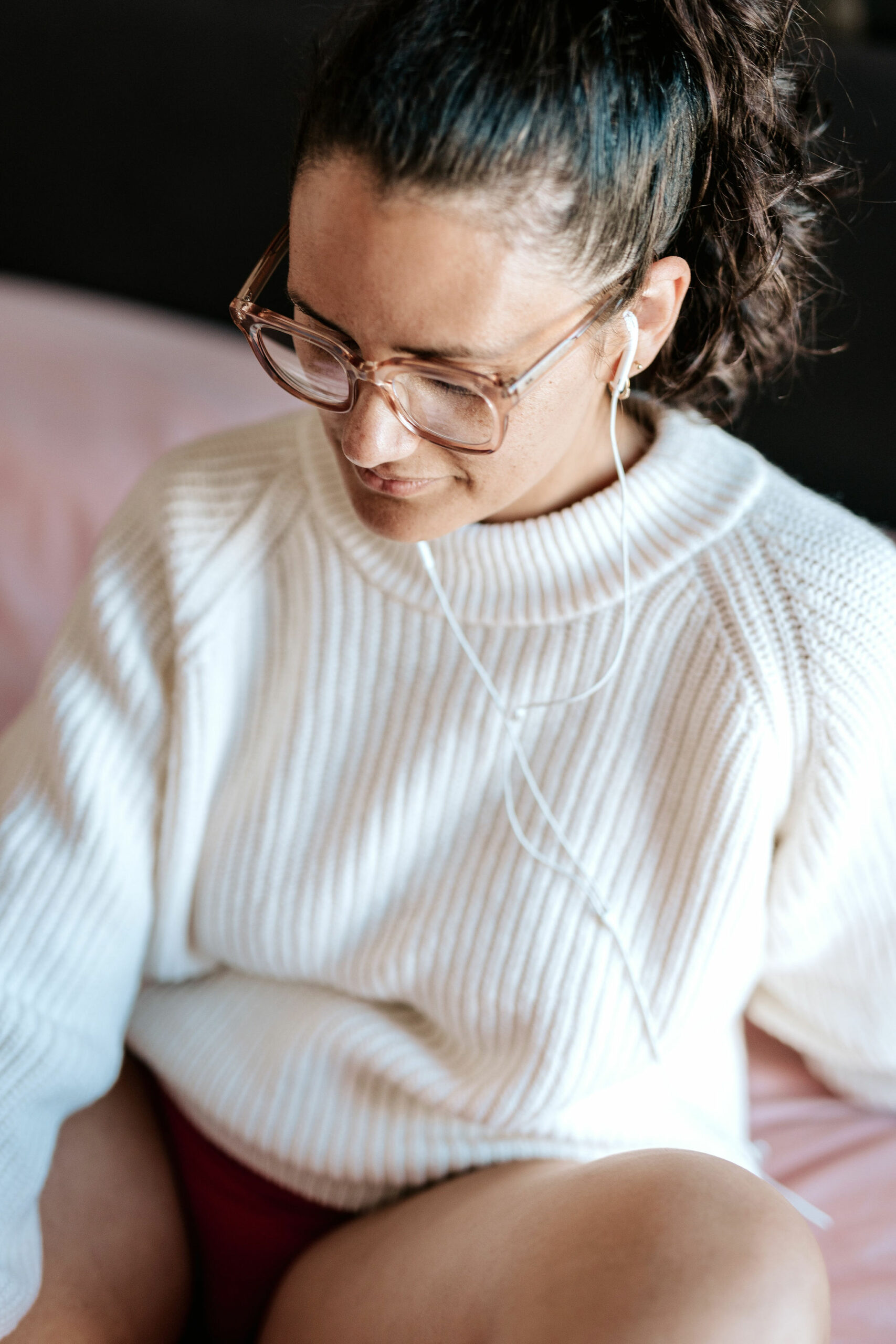 picture of steffi von brunner, she sits in easy pose on the ground and looks straight to the camera. She wears a trousers and a wrap top in a black and white flower print and wears pink transluscent glasses