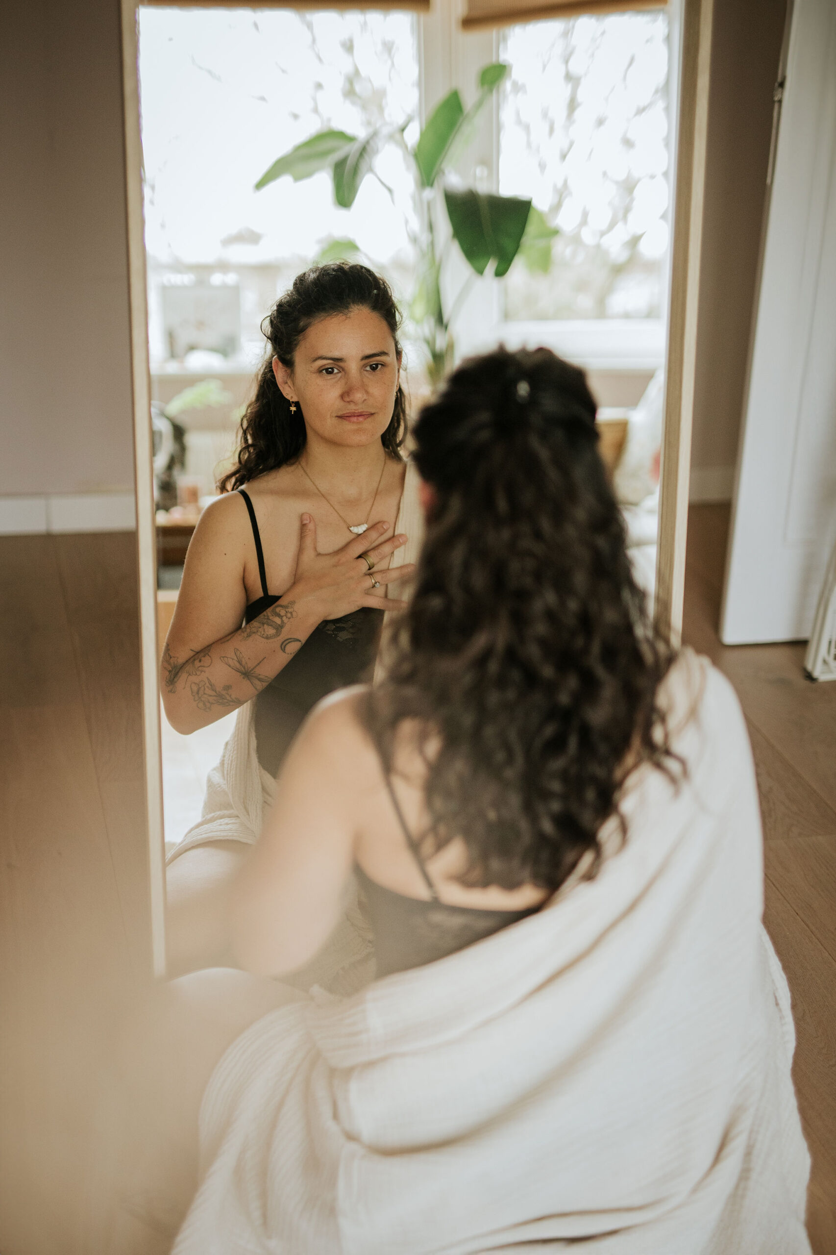 Steffi von Brunner, seksualiteitscoach Den Haag, zit voor een spiegel met haar hand op haar hart — een moment van zelfverbinding en lichaamswerk<br />

